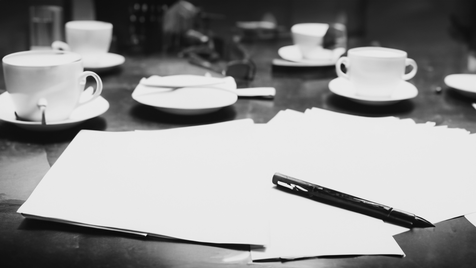 Kahvikuppeja ja papereita kokouspöydällä.