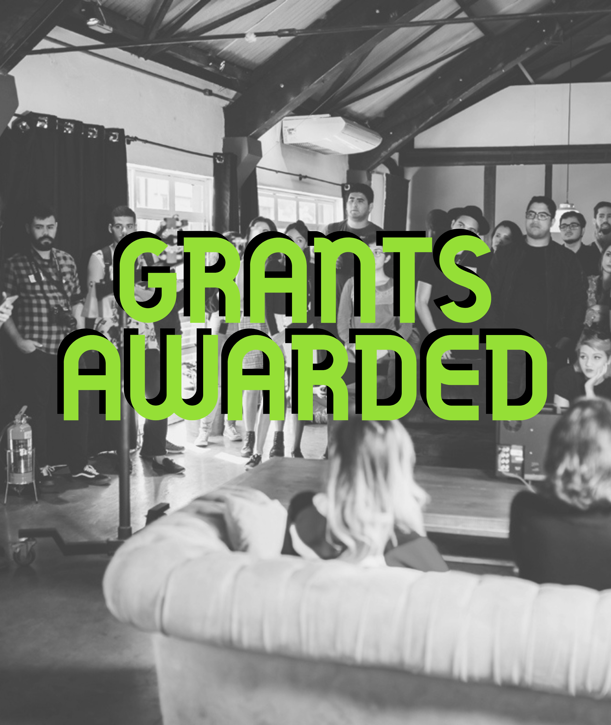 People are gathered to listen to someone. Picture says "grants awarded".